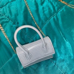Grayish-blue mini purse with gold chain.